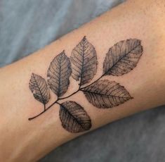 a woman's arm with a leaf tattoo on it