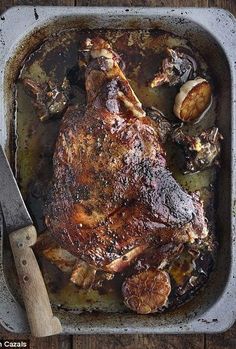 a roasting pan filled with cooked meat and vegetables on top of a wooden table