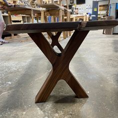 a wooden bench sitting on top of a floor next to a person in a shop