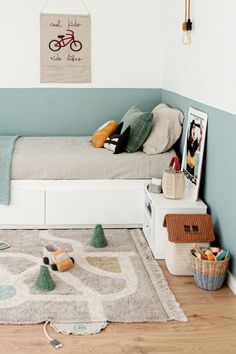 a bed room with a neatly made bed next to a rug and pictures on the wall