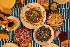 a table topped with plates and bowls filled with different types of food next to utensils