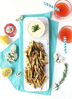 an image of french fries on a plate with dipping sauces and lemon wedges