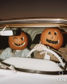 two people sitting in a car with pumpkins on their heads