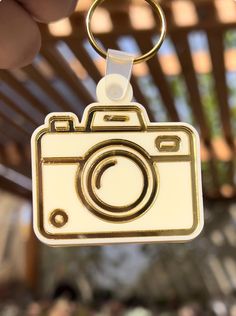 a camera keychain is being held by someone's hand