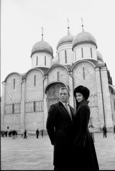 a man and woman standing in front of a large building with domes on it's sides