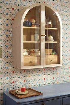 a cabinet with two glass doors on the front, and a blue table underneath it