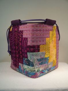 a multicolored handbag sitting on top of a white table next to a wall