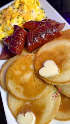 pancakes with butter, bacon and eggs on a white plate next to other breakfast foods