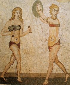 two women in bikinis playing frisbee with each other on a mosaic wall