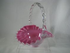 a pink glass basket sitting on top of a white table