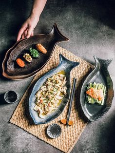 two plates with food on them sitting on a table next to a person's hand