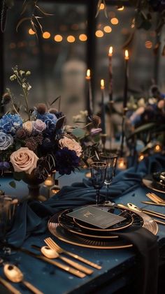 the table is set with blue and gold plates, silverware, and floral centerpieces