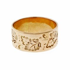 a gold ring with flowers and leaves engraved on the inside, sitting against a white background