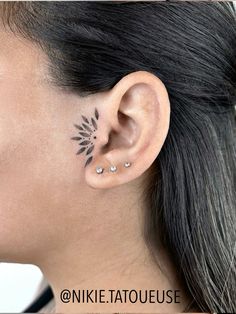 a woman's ear with an artistic tattoo design on the left side of her ear