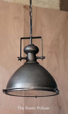 an industrial style light fixture hanging from a chain on a wood paneled wall with the words rustic pelican written below it