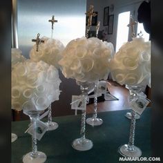 several clear vases with flowers in them on a table next to a cross and mirror