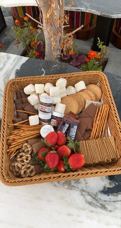 a wicker basket filled with cookies, marshmallows and strawberries