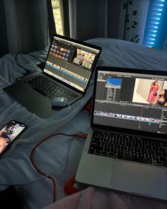 two laptops sitting on top of a bed next to each other