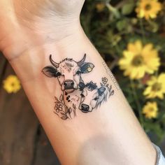 a small cow and calf tattoo on the left inner wrist, with daisies in the background