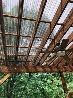 a ceiling fan is mounted to the side of a wooden structure in front of trees