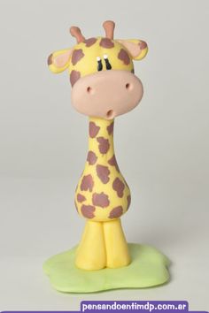 a giraffe figurine sitting on top of a green base next to a gray background