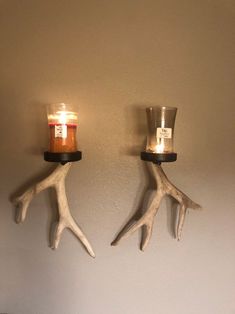 two antlers are hanging on the wall next to a candle holder with candles in it