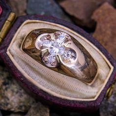 a gold and diamond ring sitting on some rocks