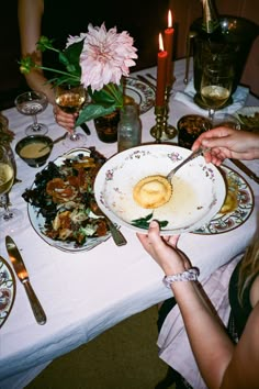 people sitting at a dinner table with plates and silverware on it, eating food