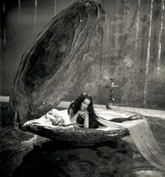 a woman laying on top of a wooden bench next to a large piece of wood