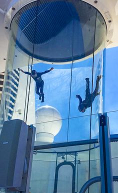 two people are reflected in the glass walls of a building