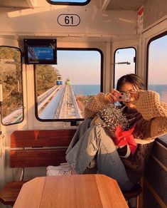 a woman taking a selfie while sitting on a train with the ocean in the background