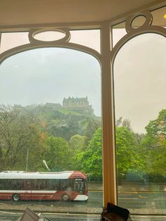 a bus is parked in front of an open window with a view of a castle