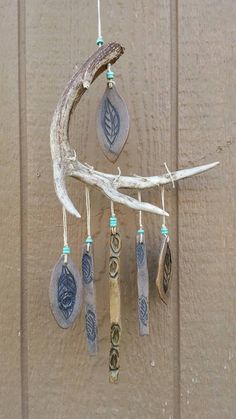 a wind chime hanging on the side of a wooden door with leaves and beads