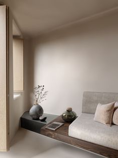 a living room filled with furniture and a vase on top of a table next to a window