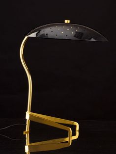 a desk lamp with a black shade on it's head and a gold stand