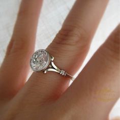 a close up of a person's hand with a diamond ring on their finger