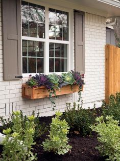 a window box filled with plants in front of a house