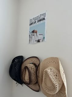 three hats are hanging on the wall next to a hat rack with a magazine cover