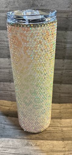 the glitter tumbler is sitting on top of a wooden table