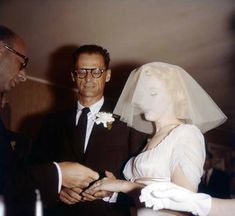 a man standing next to a woman in a white dress and veil on her head