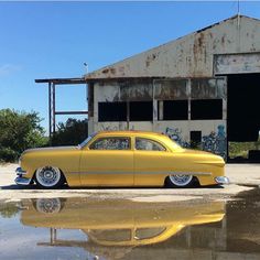 an old yellow car parked in front of a building