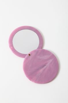 two circular mirrors sitting next to each other on a white surface, one with a round mirror in the middle