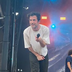 a man holding a microphone standing on top of a stage next to other people at a concert