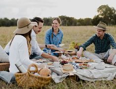 a group of people sitting on top of a grass covered field next to each other