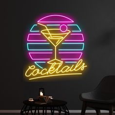 a neon sign that says cocktails on the wall next to a chair and table