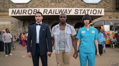 three people standing in front of a railway station