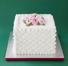 a square cake with white frosting and pink flowers on top