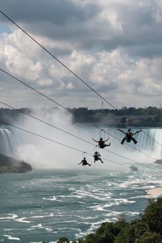 three people are zipping through the air over niagara falls, with water in the background