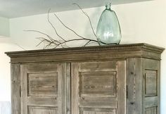 an old wooden cabinet with glass vase on top