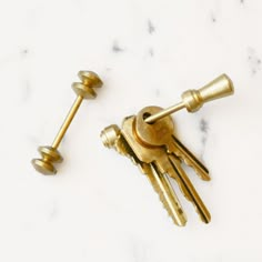 two golden keys sitting on top of a white marble counter next to some gold knobs